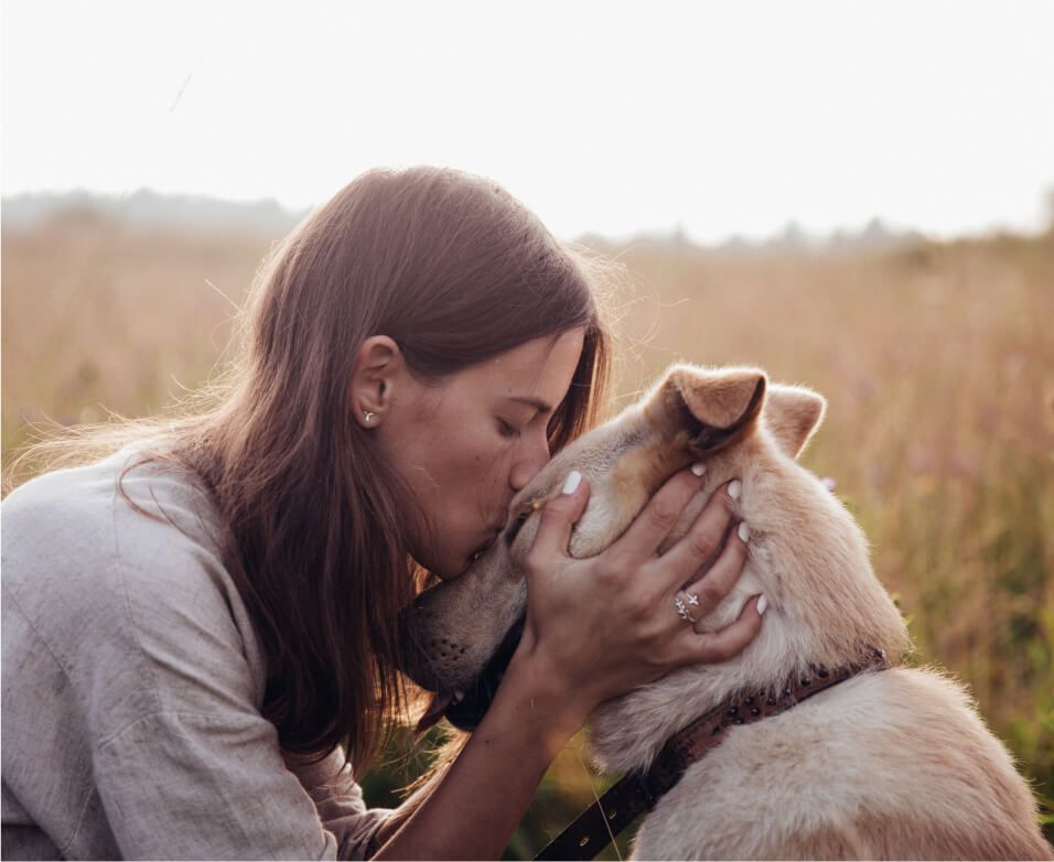 Eine Frau küsst ihren Hund auf die Stirn